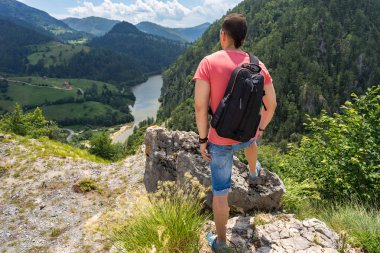 Turistik dağ üzerinde duran sırt çantası ile adam ve Spajici Gölü ve Tara Milli Parkı Zaovine, Sırbistan'ın yüksek tepelerden bak