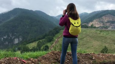 Kadın gezgin fotoğraflar doğa manzaralı yerinde yüksek poin bulutlu yağmurlu gün alır. Arkadan görünüm