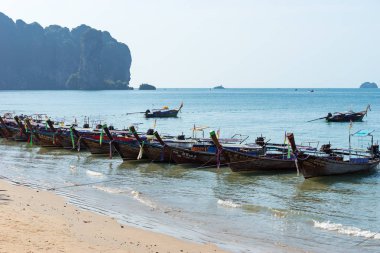 Üst üste Tay uzun kuyruklu tekneler neredeyse öğleden sonra deniz suyunda kıyıya demirlemiş