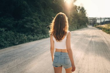 Gevşek saçlı genç bir ince kadın yolda yaz yürüyor