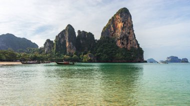 Kumlu plajın, berrak denizin, kıyı şeridinin, kayaların ve teknelerin sabahları sudaki manzaraları