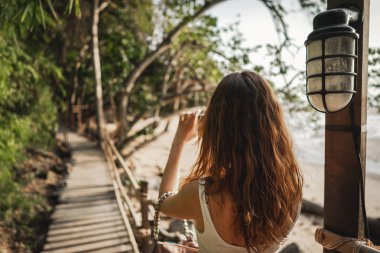 Kadın akıllı telefonuyla ahşap patika maymun patikasının fotoğrafını çekiyor.