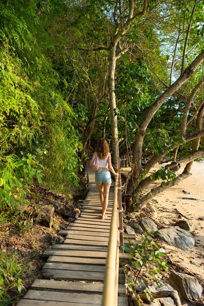 Young woman goes on wooden pathway Monkey Trail to Pai Plong beach