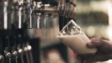 El bir cam tutarak ve musluk zanaat pub azot bira dökün. Ön bakış. Bokeh arka plan bulanık. Yavaş hareket
