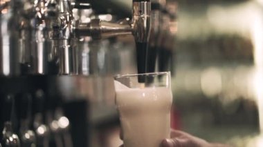 El bir cam tutarak ve musluk zanaat pub azot bira dökün. Ön bakış. Bulanık arka plan. Yavaş hareket