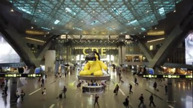 Doha, Katar - 11 Ocak 2019: Hamad uluslararası havaalanı terminali büyük sarı ayıile. Hareket eden insanlarda yüksek açı görünümü