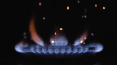 Gaz mavisi soba alevi karanlıkta yanıyor. Yavaş çekim. Parçacıklar uçar ve ateşte yanar.