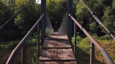 Güneşli bir sabahta kırsal alanda eski ahşap bir köprü. Bakış açısı. Kamera ileri gidiyor.