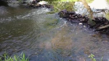 Rus kırsalındaki bir nehirde taş bir baraj. Kırsalda su akıntısı yavaşça akar.