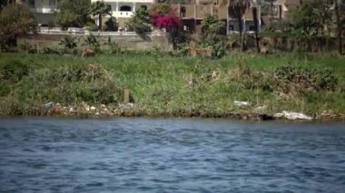 LUXOR, EGYPT - 5 Nisan 2019: Nil Nehri 'ndeki bir tekneden kıyı manzarası, kıyı boyunca çöp. Çevre kirliliği, çevre sorunu. Mısır