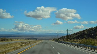 New Mexico 'daki dağlık bir vadide düz bir yol, ufukta beyaz bulutlar, ABD