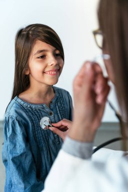 Doktor steteskopla küçük bir kızı muayene ediyor. İlaç ve sağlık hizmetleri kavramı.