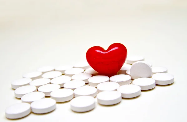 白色的白色药丸与红色心脏在白背景 — 图库照片