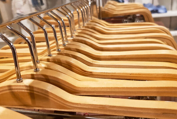 Detail of clothes hanging on wooden hangers in a fashion store.