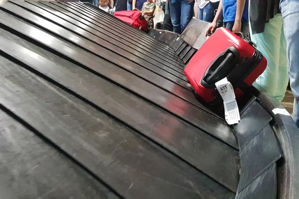 Wheeled suitcase on a luggage belt at the airport terminal