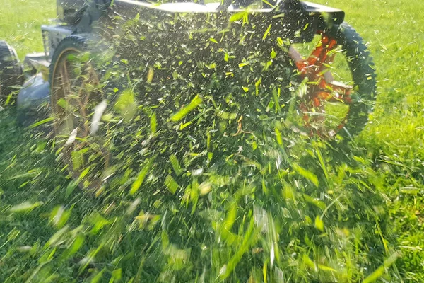 芝生芝刈り機から飛ぶ草を刈る — ストック写真
