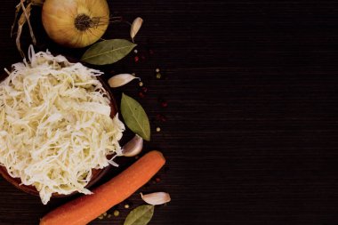 Boşaltmak karanlık bir ahşap zemin üzerine defne yaprağı ve baharat ile havuç soğan ile marine edilmiş lahana rulo