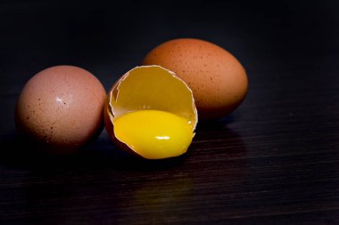 Üç taze tavuk yumurta karanlık bir arka planda yarıya iner.