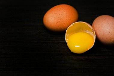 Üç taze tavuk yumurta karanlık bir arka planda yarıya iner.