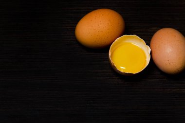 Üç taze tavuk yumurta karanlık bir arka planda yarıya iner.