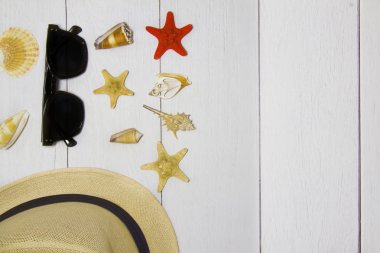 Seyahat kavramı - oyuncak tekne, şapka, güneş gözlüğü, çeşitli egzotik deniz kabukları ve diğer deniz hazineleri açık ahşap arka planda, tepeden kum manzaralı.