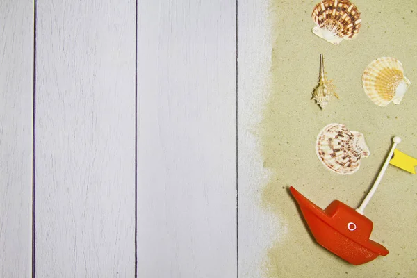 Tengeri kagyló, csillag, játék hajó, a világos fából készült háttér homokkal, felülnézet — Stock Fotó