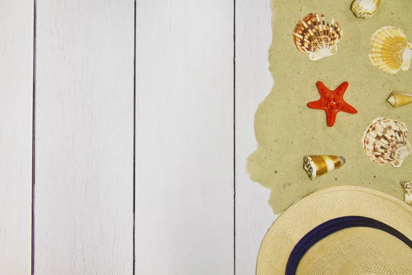 Conchiglie, stelle, cappello su uno sfondo di legno chiaro con sabbia, vista dall'alto — Foto Stock