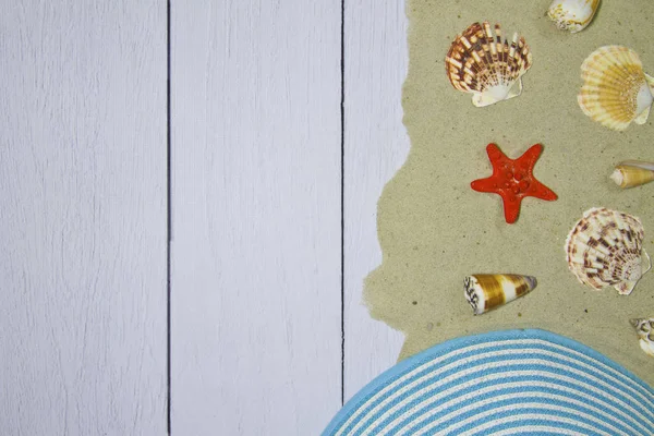 Морські раковини, зірки, капелюх на світлому дерев'яному тлі з піском, вид зверху — стокове фото