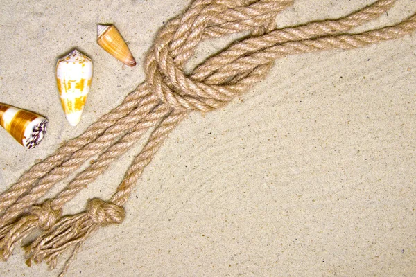 Muscheln und nautische Seildekoration auf Sandgrund mit rotem Spielzeugschiff — Stockfoto