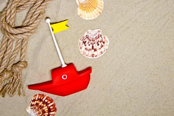 Морські черепашки та прикраси з морської мотузки на піщаному фоні з червоним іграшковим кораблем — стокове фото
