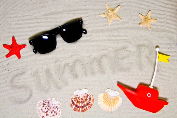 Yaz yazıtlı berrak deniz kumu, metin ve üst görünüm için alan. Deniz kabukları ve güneş gözlüğü ile yaz tatili arka plan