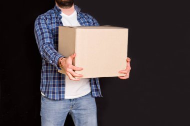 Genç paket teslimatçısı elinde bir karton kutu tutuyor..