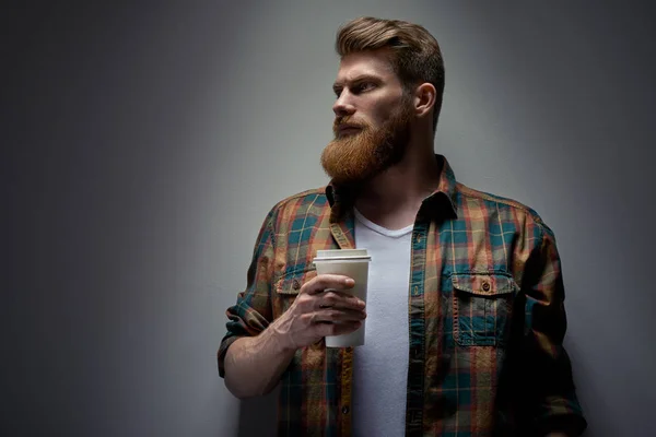 Bearded man drinking cappuccino coffee to go