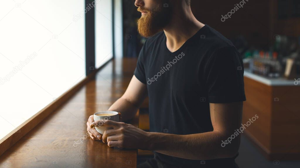 Close up shot of men's hands holding a mug of coffee Resting handsome perfect hairstyle man drinking espresso coffee. Bearded man holding cup of coffee indoors