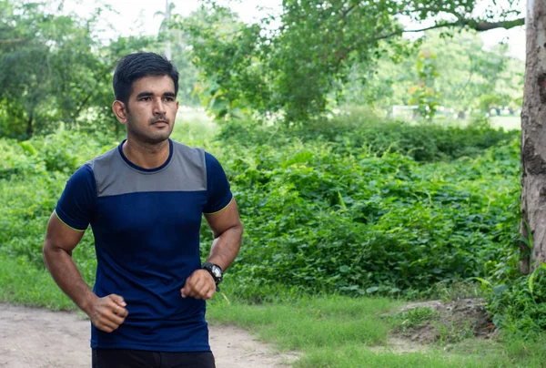 Young indian man running in ground. Male fitness and health concept.