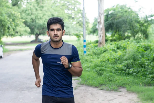 Young indian man running in ground. Male fitness and health concept.