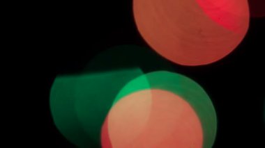Bokeh Eski Lens. Siyah bir arkaplanda yavaşça sağdan sola hareket eden çok renkli yanıp sönen büyük bir bokeh.