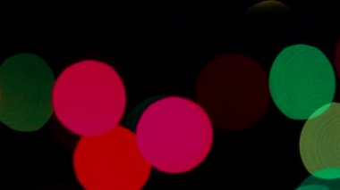 Holiday Lights odak içinde. Yavaş yavaş hareketli çeşitli renklerde yanıp sönen ışık soldan sağa bir siyah arka plan üzerine