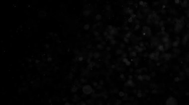 Microparticles uçuş. Küçük beyaz parçacıklar kar, kar fırtınası veya Noel sihirli bir evren benzetimini yapmak için siyah arka plan üzerinde hava akışı. 240 fps hızında filme