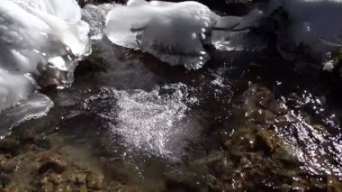 Bir kayaya hızlı dağ nehir ortasında donmuş su. Ağır çekim 240 fps hızında