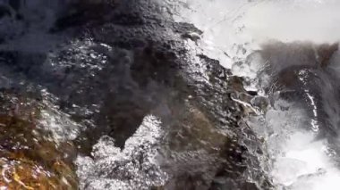 Bir kayaya hızlı dağ nehir ortasında donmuş su. Ağır çekim 240 fps hızında