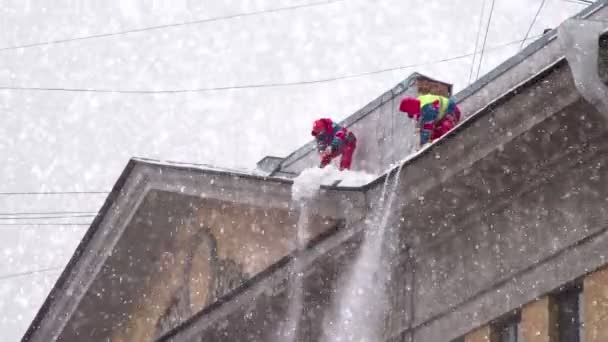 大雪の中に背の高い歴史的な建物の屋根から雪をオフに産業登山 — ストック動画