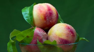 Olgun, sulu şeftali bir cam bardak yavaş yavaş koyu yeşil bir arka plan üzerinde döner