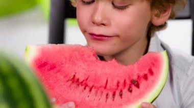Komik bir kıvırcık saçlı çocuk karpuz büyük bir parça keyifle yiyor
