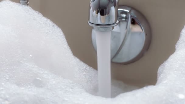水龙头里的一股水流充满了浴缸 水面上覆盖着厚厚的泡沫 — 图库视频影像