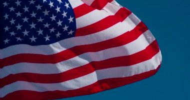 Büyük Devlet Bayrağı güneş tarafından aydınlatılır ve mavi gökyüzüne karşı rüzgarda destansı bir şekilde çırpınır. Yavaş Çekim 120 fps