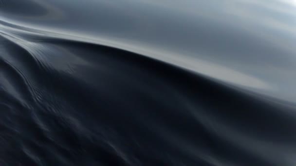 Le nez du bateau coupe lentement à travers l'eau calme et crée des vagues sombres vacillantes. Mouvement lent à 240 ips 