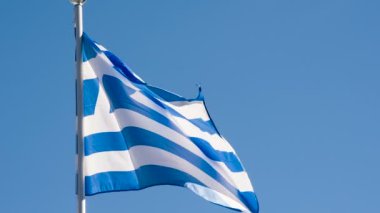Yunanistan Bayrağı Rüzgarı Kıpırdatıyor. Büyük Eyalet Bayrağı güneş tarafından aydınlatılır ve mavi gökyüzüne karşı destansı bir şekilde dalgalanır. Slow Motion 240 fps