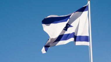 İsrail bayrağı rüzgarı sallıyor. Büyük Eyalet Bayrağı güneş tarafından aydınlatılır ve mavi gökyüzüne karşı destansı bir şekilde dalgalanır. Slow Motion 240 fps