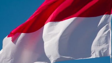 Güneşin Endonezya Bayrağı Edebiyatı. Büyük Eyalet Bayrağı güneş tarafından aydınlatılır ve mavi gökyüzüne karşı destansı bir şekilde dalgalanır. Slow Motion 240 fps